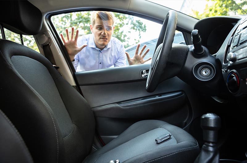 Man locked out of car looking at remote on seat
